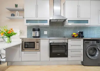 a kitchen with white cabinets and a stove top oven at The Tygervalley Escape in Cape Town