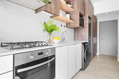a white kitchen with a stove and a sink at Studio on North in Cape Town