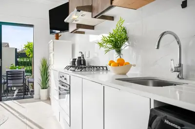 a kitchen with white cabinets and a sink with oranges on the counter at Studio on North in Cape Town