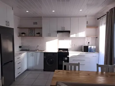 a kitchen with white cabinets and a sink and a table at Garden studio flat in Panorama