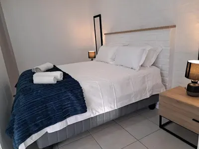 a bedroom with a white bed with towels on it at Garden studio flat in Panorama
