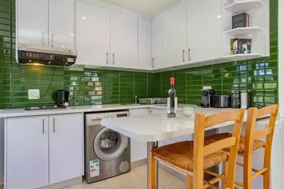a kitchen with white cabinets and green tiles at Calais Wine Estate in Paarl