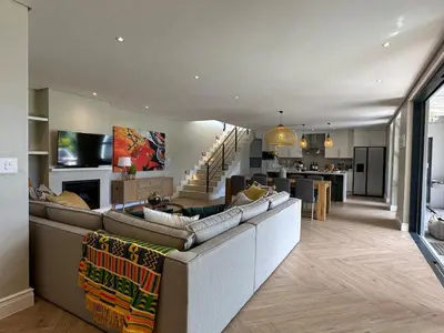 a living room with a large couch and a kitchen at Luxury Home in Security Golf Estate with Ocean Terrace in Cape Town