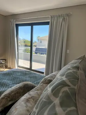 a bedroom with a bed and a large window at Luxury Home in Security Golf Estate with Ocean Terrace in Cape Town