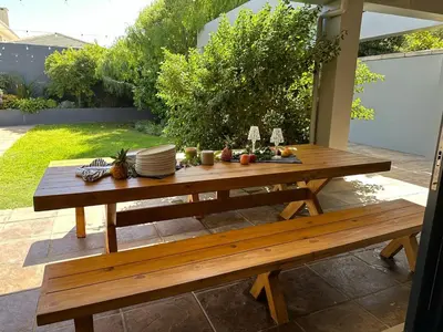 a wooden picnic table with plates and dishes on it at Luxury Home in Security Golf Estate with Ocean Terrace in Cape Town