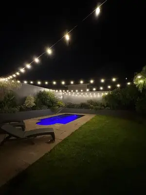 a backyard with a pool at night with lights at Luxury Home in Security Golf Estate with Ocean Terrace in Cape Town