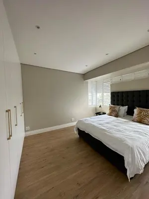 a large bedroom with a large bed and wooden floors at Luxury Home in Security Golf Estate with Ocean Terrace in Cape Town