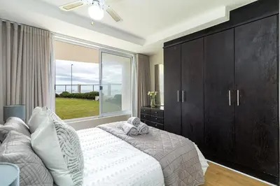 a bedroom with a bed and a large window at 2 Bedroom Seaview, Holiday Apartment, Lagoon Beach in Cape Town