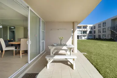 a patio with a table and chairs on a lawn at 2 Bedroom Seaview, Holiday Apartment, Lagoon Beach in Cape Town