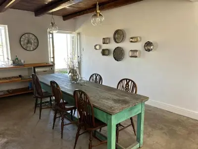 a dining room with a green table and chairs at Ceres Hideaways