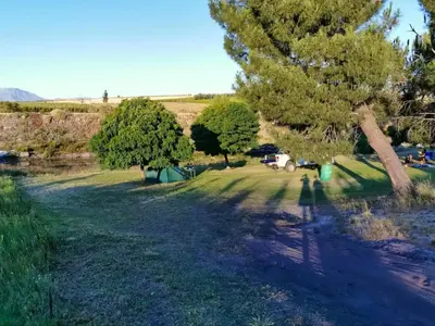 a field with trees and a campsite in the distance at Ceres Hideaways