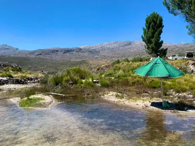 a green umbrella sitting on a beach with water at Ceres Hideaways