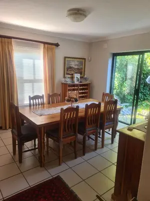 a dining room with a wooden table and chairs at Fairway Corner in Villiersdorp