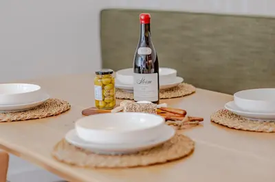 a table with white plates and a bottle of wine at Chic Coastal Hideaway in Hermanus