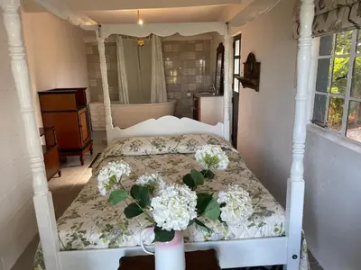 a bedroom with a bed with white flowers on it at Honeymoon Stay at The James Family Farm in Grabouw