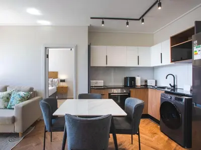 a kitchen and living room with a table and chairs at On Park Century City in Cape Town