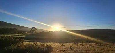 a sun is setting over a field with the sun shining at Hoopoe Cottage Horns op de Hoek in Hartebeest Rivier