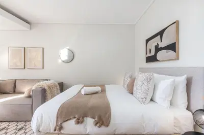 a white bedroom with a bed and a couch at On Park - Century City Lux Studio Apartment in Cape Town