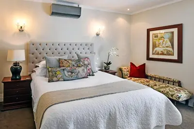 a bedroom with a large bed and a chair at Le Petit Bijou Aparthotel in Franschhoek