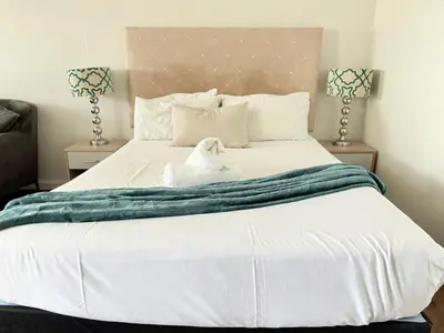 a white dog sitting on top of a bed at Luxe Studio - On Park near Canal walk Century City in Cape Town