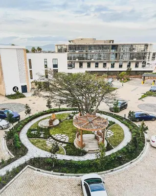 a large building with a garden in the middle of a park at Luxe Studio - On Park near Canal walk Century City in Cape Town