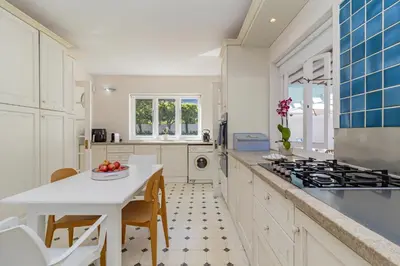 a kitchen with white cabinets and a table and a sink at Escape to Hermanus Spacious Family Home in Hermanus