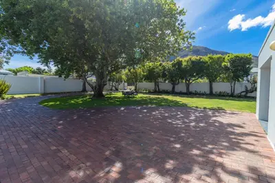 a brick driveway with a tree in a yard at Escape to Hermanus Spacious Family Home in Hermanus