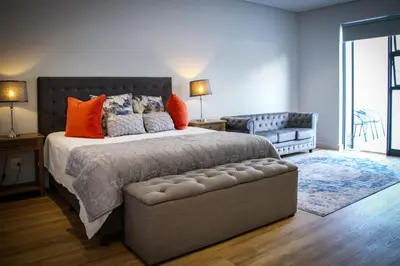 a bedroom with a large bed with orange pillows at Upmarket Room in Stellenbosch