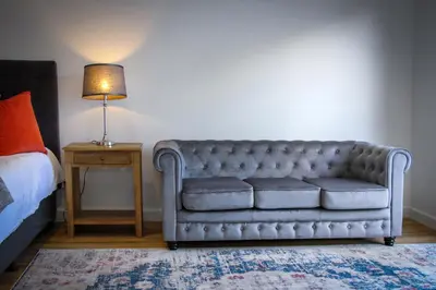 a couch in a bedroom with a bed and a lamp at Upmarket Room in Stellenbosch