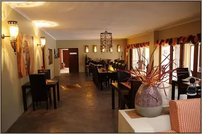 a dining room with a table and chairs and a vase at Kapensis Guesthouse II Venue & self-catering in Bettyʼs Bay