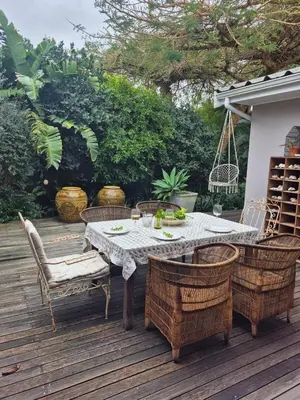 a dining table and chairs on a wooden deck at Serendipity 2 Bedroom Family Home in Onrus in Hermanus