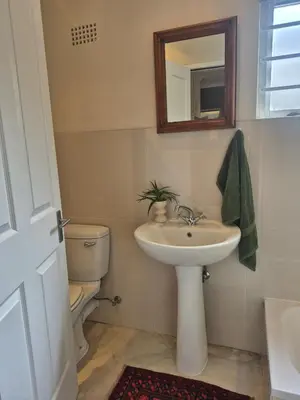 a bathroom with a sink and a toilet and a mirror at Serendipity 2 Bedroom Family Home in Onrus in Hermanus