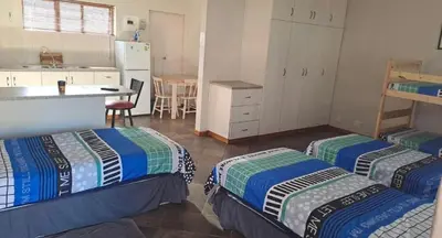 a room with two beds and a kitchen with a table at Sir Garnet Inn in Wolseley