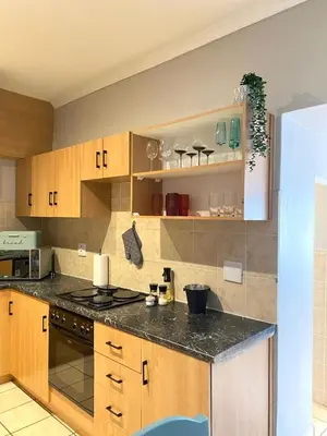 a kitchen with wooden cabinets and a black counter top at Nunu's Self Catering Apartment in Paarl