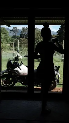 a woman standing in front of a window looking at a motorcycle at Apple Cottage in Grabouw