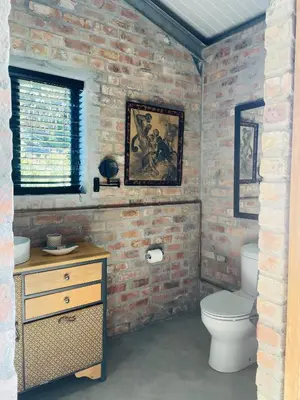 a brick walled bathroom with a toilet and a sink at Apple Cottage in Grabouw