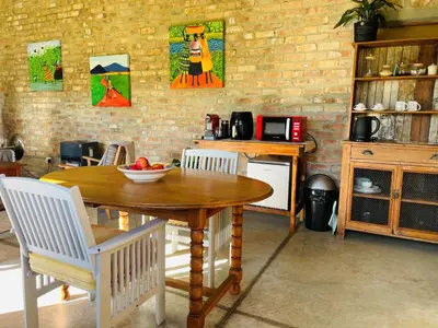 a kitchen with a wooden table and white chairs at Apple Cottage in Grabouw