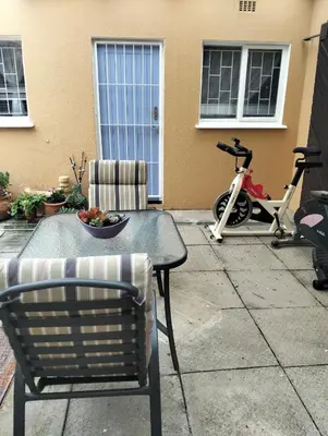 a table and chairs with a bowl of fruit and a scooter at Impletio in Gordonʼs Bay