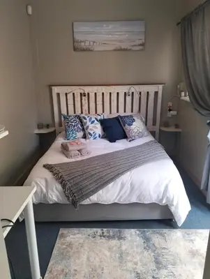 a bedroom with a white bed with pillows on it at Impletio in Gordonʼs Bay