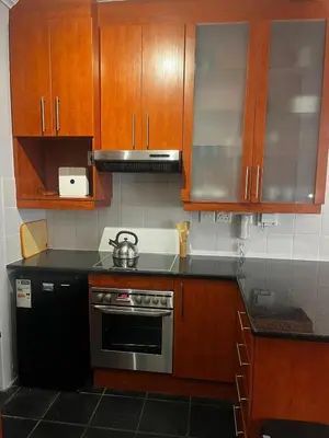 a kitchen with wooden cabinets and a stove at Live Like a Local in Stellies - By ARPA Hospitalities in Stellenbosch
