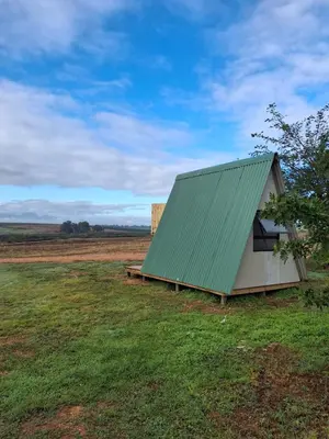 a small green roofed building in a field at Blouporselein guestfarm cabin in Hermon