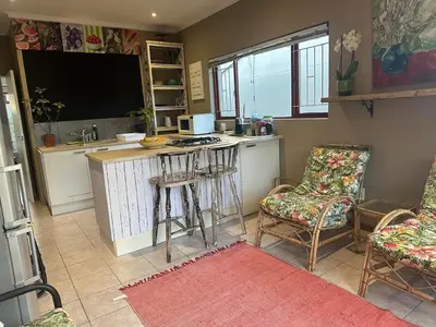 a kitchen with a stove and a counter with chairs at Winelands Beach Cottage in Gordonʼs Bay
