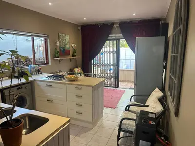 a kitchen with a sink and a refrigerator and a stove at Winelands Beach Cottage in Gordonʼs Bay