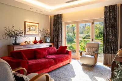 a living room with a red couch and a window at Stellenbosch Farm Stay with Mountain Views & Pool in Stellenbosch