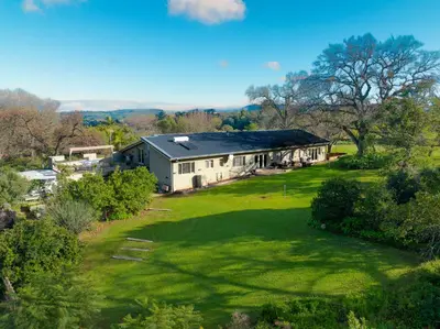 an aerial view of a house with a green yard at Stellenbosch Farm Stay with Mountain Views & Pool in Stellenbosch