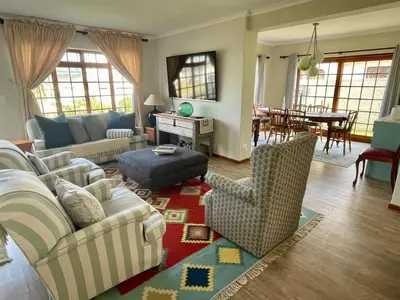 a living room with a couch and chairs and a table at Voelklip Holiday Home in Hermanus