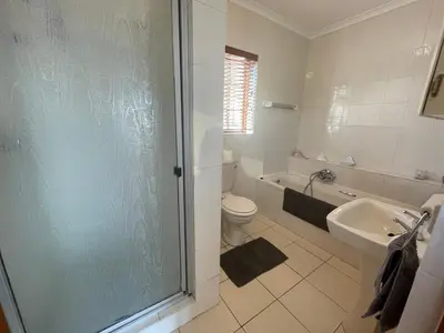 a bathroom with a shower and a toilet and a sink at Voelklip Holiday Home in Hermanus