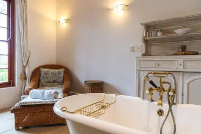 a bath tub in a room with a chair at The Neighbours Farm - Homestead in Stellenbosch
