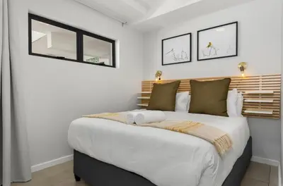 a bedroom with a large white bed with two windows at Beautiful Beach Break! in Cape Town