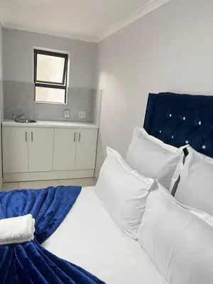 a bedroom with a bed with a blue headboard and white pillows at The Perfect Place in Parow